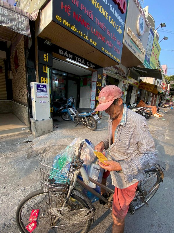 Hoa hậu Võ Thu Sương cúi xuống thật gần với người bán vé số, ve chai