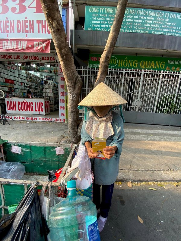 Hoa hậu Võ Thu Sương cúi xuống thật gần với người bán vé số, ve chai