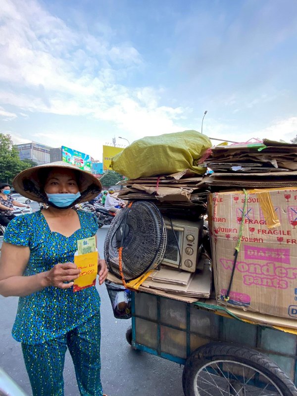 Hoa hậu Võ Thu Sương cúi xuống thật gần với người bán vé số, ve chai